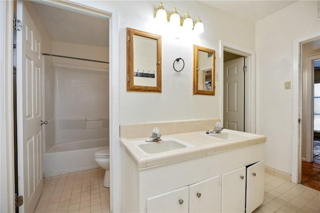 full bath featuring toilet, tile patterned flooring, double vanity, and a sink