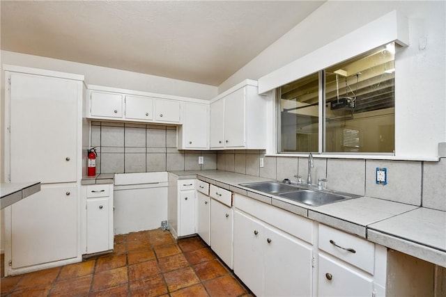 kitchen with white cabinets, a sink, and backsplash