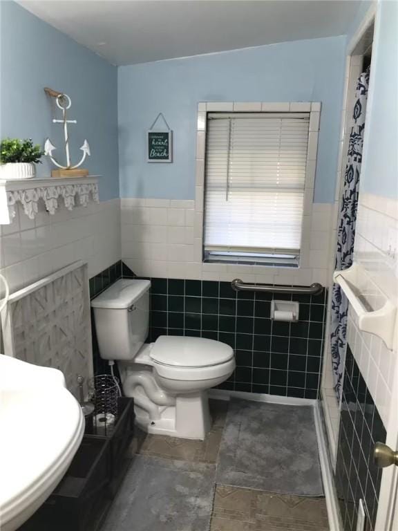 bathroom featuring tile walls, a wainscoted wall, a shower with curtain, and toilet