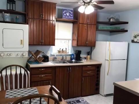 kitchen with open shelves, freestanding refrigerator, a ceiling fan, and a sink