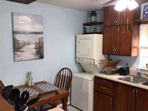 laundry room featuring laundry area, stacked washer and clothes dryer, a sink, and ceiling fan
