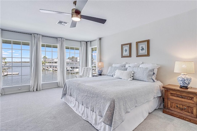 carpeted bedroom with access to outside, a water view, and ceiling fan