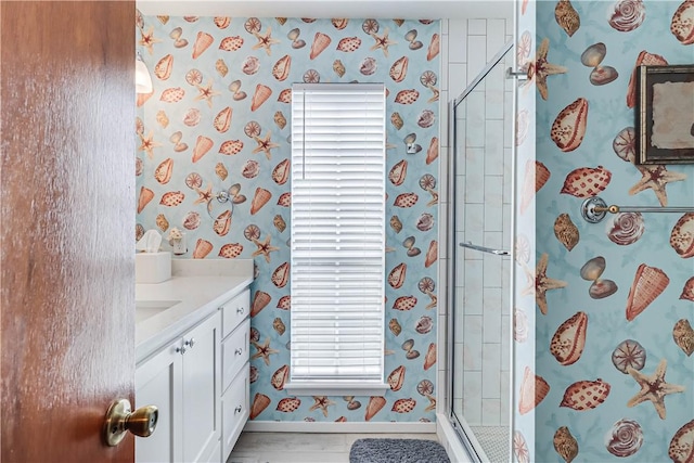 bathroom featuring a shower with door and vanity