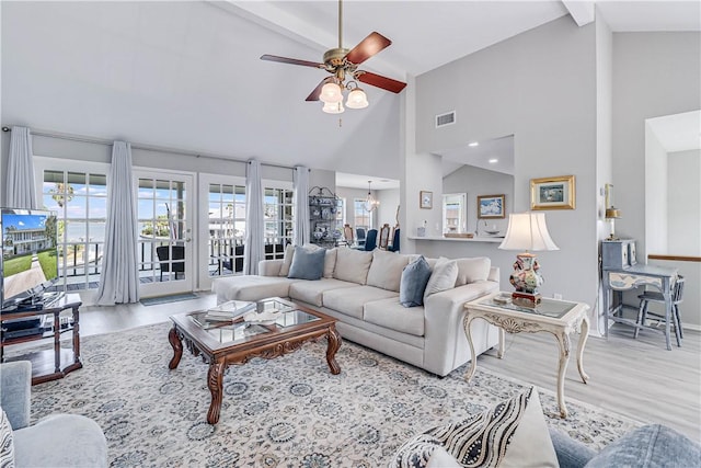 living room featuring light hardwood / wood-style floors, a healthy amount of sunlight, and ceiling fan with notable chandelier