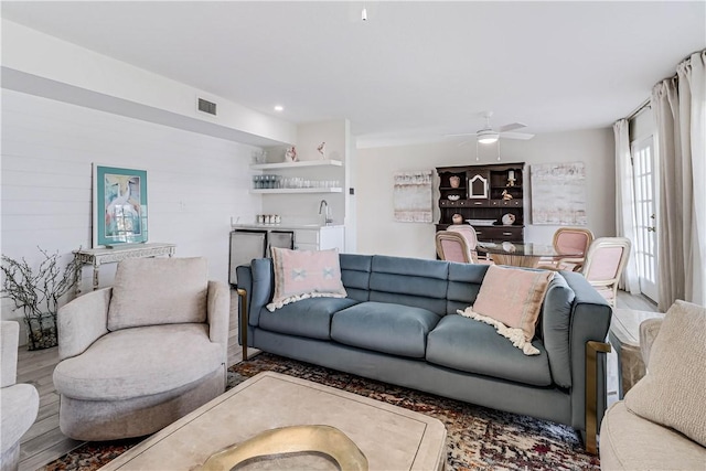 living room featuring hardwood / wood-style floors, ceiling fan, and wet bar