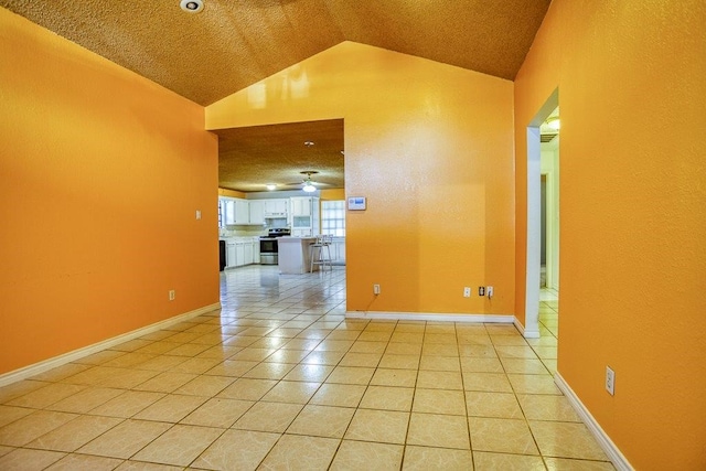 tiled spare room with ceiling fan, a textured ceiling, and vaulted ceiling