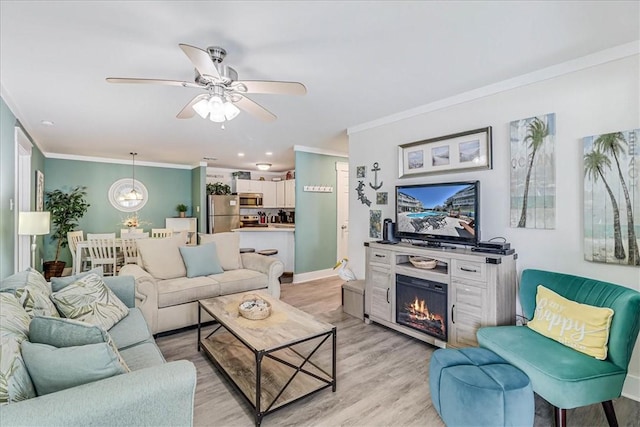 living room featuring ornamental molding, ceiling fan, and light wood-type flooring