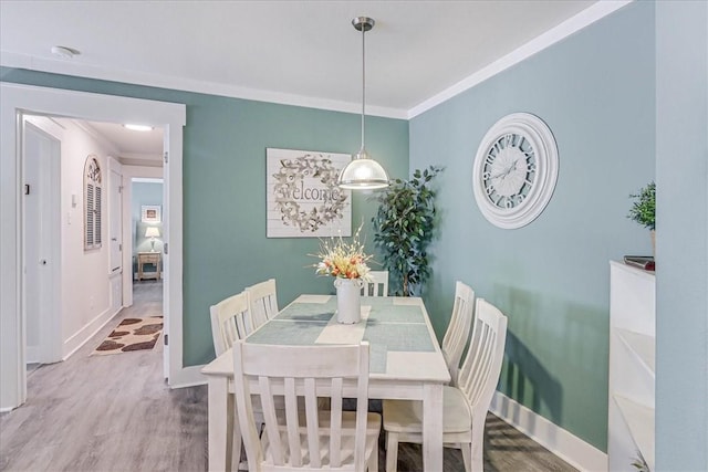 dining space with hardwood / wood-style flooring and ornamental molding