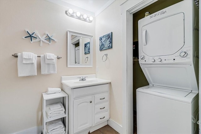 clothes washing area featuring tile patterned flooring, stacked washer / drying machine, and sink