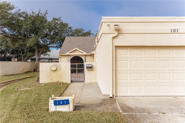 view of front facade with driveway, stucco siding, a gate, fence, and a front yard