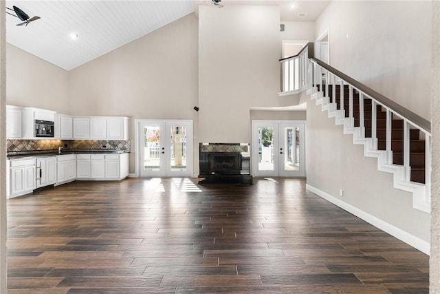 unfurnished living room featuring french doors, dark hardwood / wood-style floors, and a high ceiling