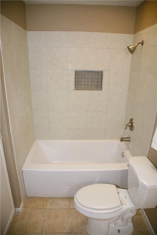 bathroom featuring tile patterned flooring, tiled shower / bath combo, and toilet