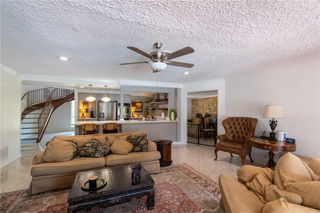 living room with ceiling fan, a textured ceiling, and crown molding