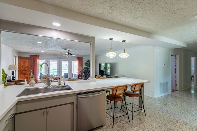 kitchen with a textured ceiling, sink, stainless steel dishwasher, a breakfast bar, and pendant lighting