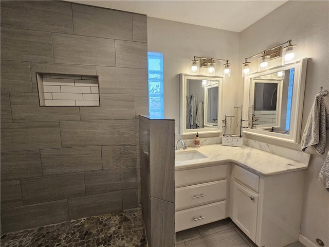 full bath with tile patterned floors, tiled shower, and vanity