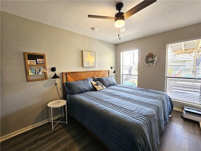 bedroom with dark wood-style flooring, a textured wall, ceiling fan, a textured ceiling, and baseboards