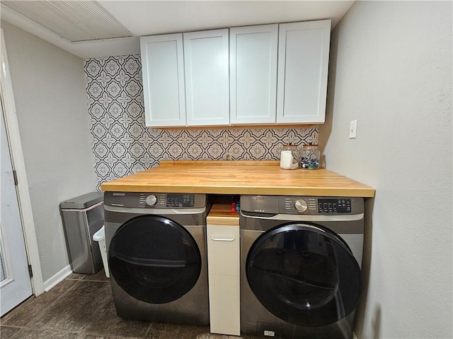 laundry room with cabinet space, baseboards, separate washer and dryer, and dark tile patterned flooring