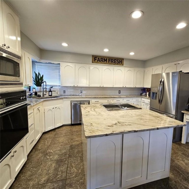 kitchen with recessed lighting, a sink, white cabinets, a center island, and black appliances