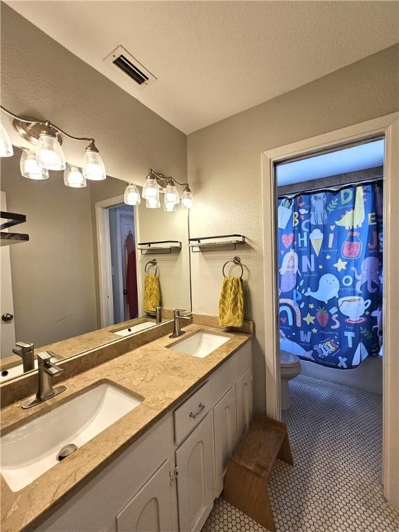 bathroom with toilet, visible vents, and a sink