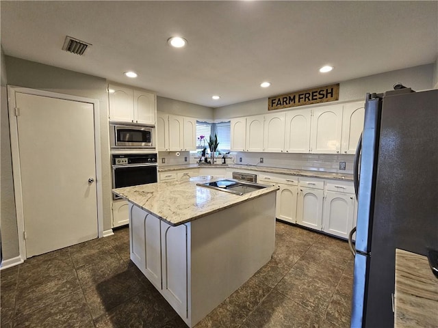 kitchen featuring a center island, visible vents, white cabinets, light stone countertops, and black appliances