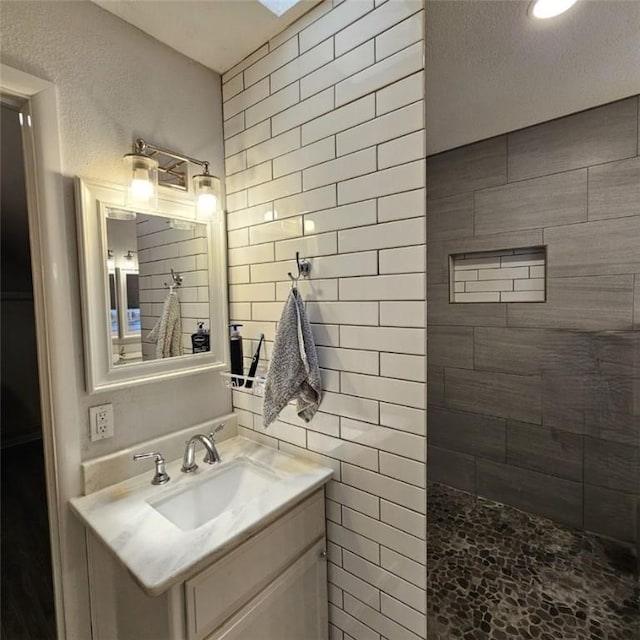 bathroom featuring a tile shower and vanity