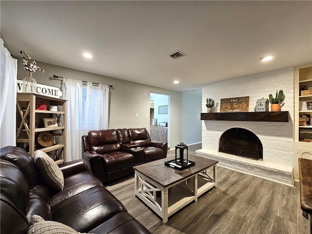 living area with recessed lighting, visible vents, a fireplace, and wood finished floors