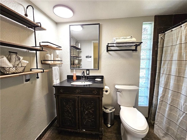 bathroom featuring a textured wall, curtained shower, vanity, and toilet