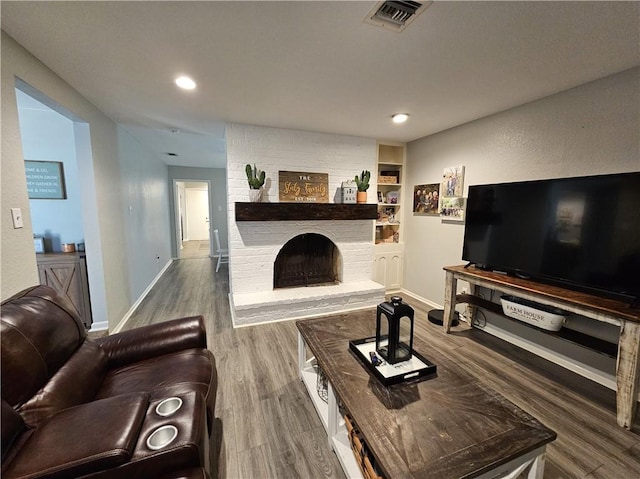 living area featuring recessed lighting, visible vents, a brick fireplace, wood finished floors, and baseboards