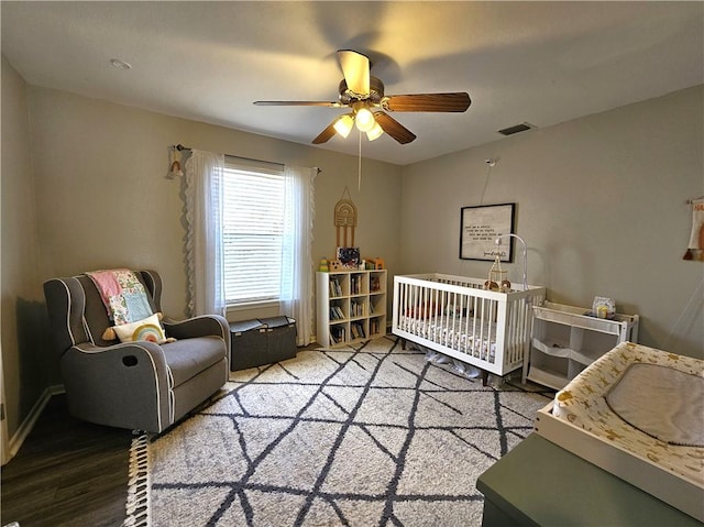 bedroom with ceiling fan, visible vents, and wood finished floors