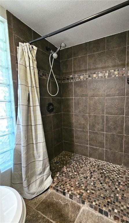 bathroom featuring a textured ceiling and tiled shower