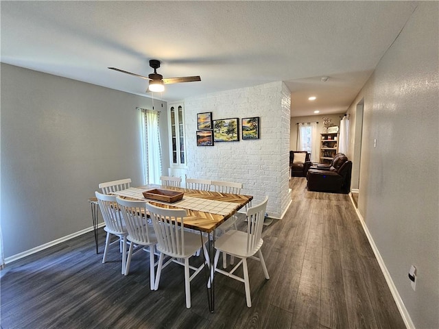 dining area with a textured ceiling, dark wood-style flooring, a ceiling fan, and baseboards