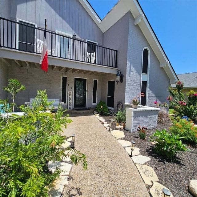 view of front of home featuring brick siding and a balcony