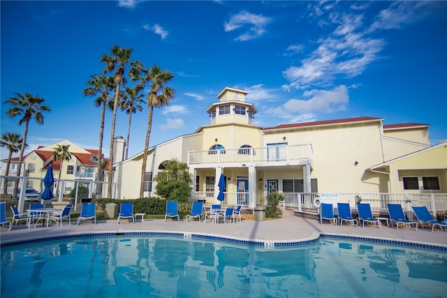 back of house featuring a patio, a balcony, and a community pool