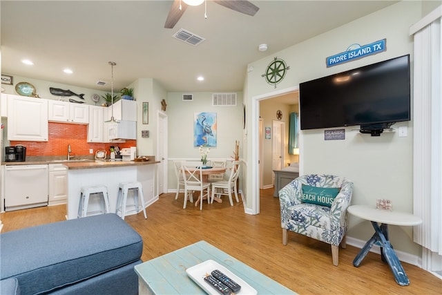 living room featuring ceiling fan, sink, and light hardwood / wood-style floors