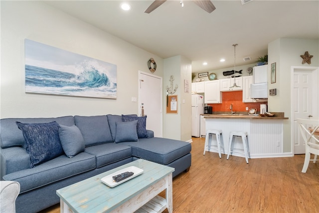 living room featuring light hardwood / wood-style flooring, ceiling fan, and sink