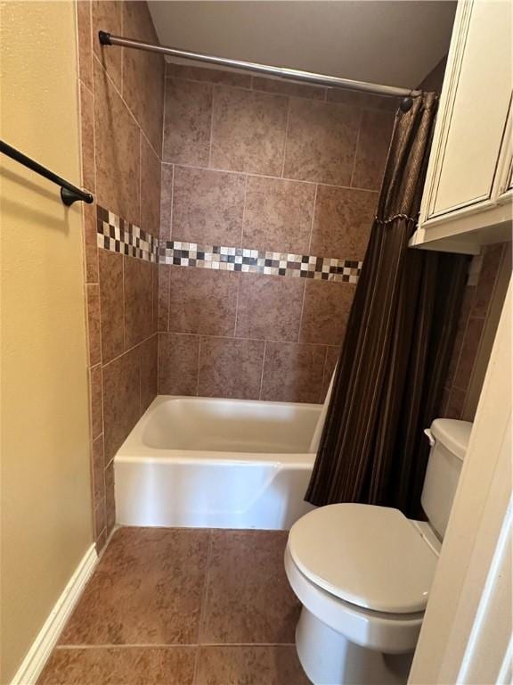 bathroom featuring tile patterned floors, toilet, baseboards, and shower / bath combo with shower curtain