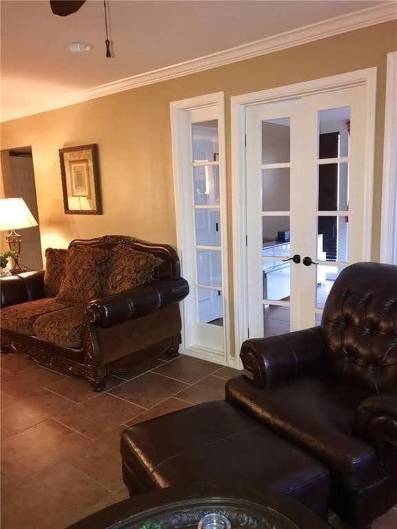 living room featuring crown molding, dark tile patterned floors, and french doors