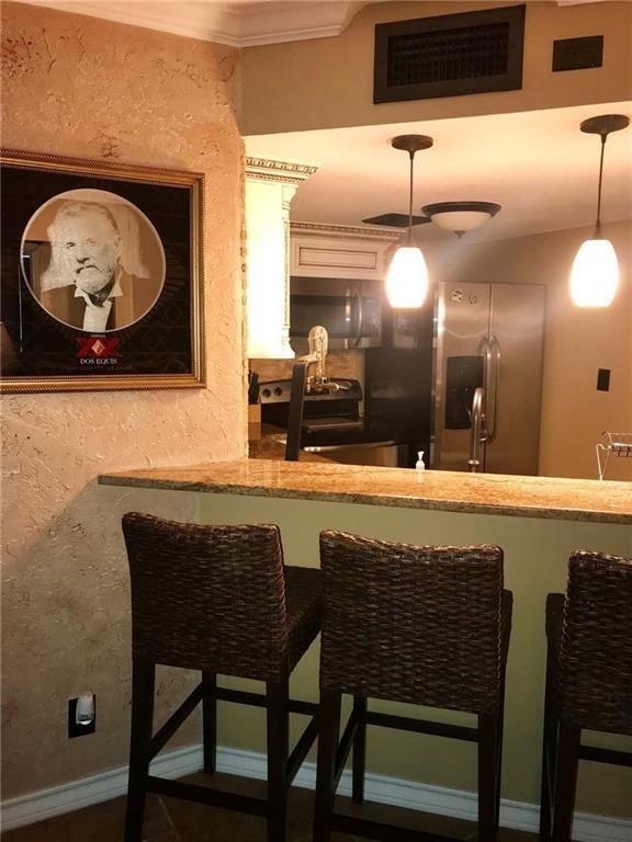 bar featuring visible vents, indoor wet bar, hanging light fixtures, stainless steel appliances, and a sink