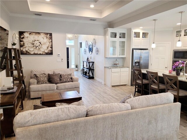 6721 Sharks Ct, Corpus Christi, TX 78414 - living area featuring light wood-type flooring, a chandelier, recessed lighting, a tray ceiling, and ornamental molding