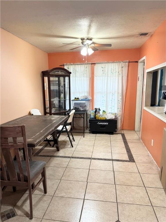 tiled dining room with a textured ceiling and ceiling fan