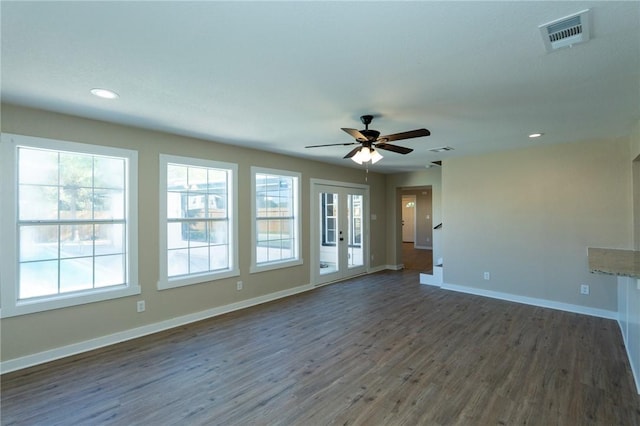 spare room with plenty of natural light, a ceiling fan, visible vents, baseboards, and dark wood finished floors