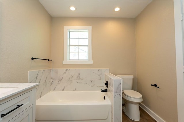 full bath with a garden tub, baseboards, toilet, wood finished floors, and vanity