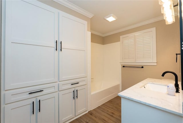 interior space with wood finished floors, a bathing tub, ornamental molding, and vanity