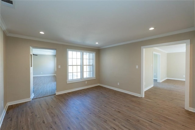 empty room featuring wood finished floors, visible vents, crown molding, and baseboards