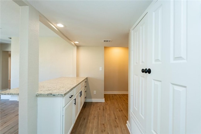 corridor with light wood finished floors, recessed lighting, visible vents, and baseboards