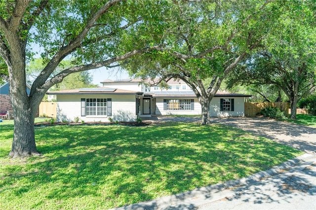ranch-style house featuring fence, roof mounted solar panels, and a front yard