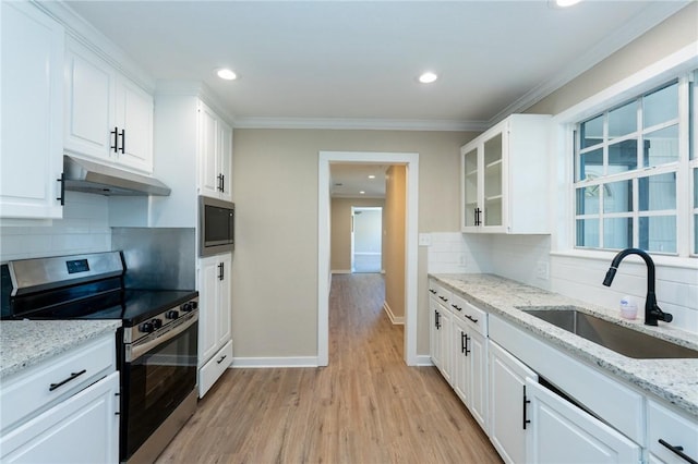 kitchen with tasteful backsplash, light wood-style flooring, a sink, appliances with stainless steel finishes, and under cabinet range hood