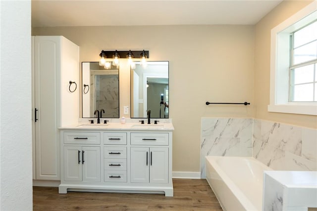 bathroom featuring a shower stall, double vanity, a bath, and a sink