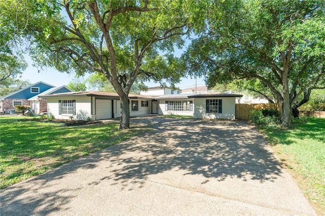 ranch-style home with a front yard, driveway, a garage, and fence