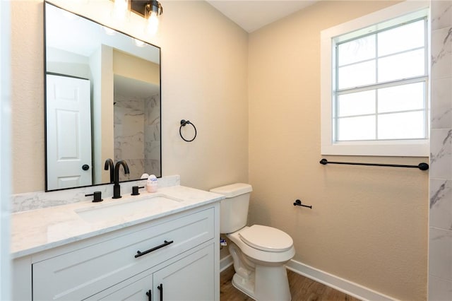 bathroom with vanity, toilet, a marble finish shower, baseboards, and wood finished floors